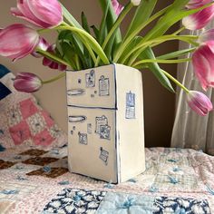 a vase filled with pink flowers sitting on top of a bed