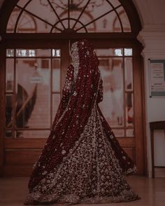 a woman in a red and white bridal gown standing in front of a doorway