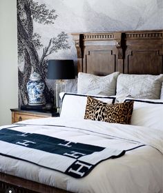 a bed with white sheets and pillows in a bedroom next to a painting on the wall