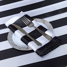 black and white striped table cloth with fork and knife on plate next to utensils