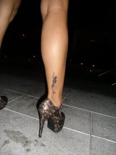 a woman's foot with a tattoo on her left leg and black lace high heels