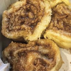 some food is sitting in a box on top of a table and it looks like cinnamon rolls