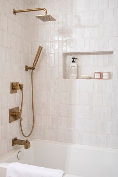 a bath tub with a shower head and hand held faucet