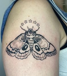 a small moth tattoo on the back of a woman's left shoulder and arm