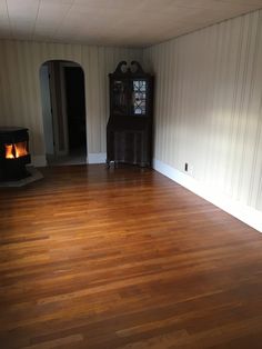 an empty room with wood floors and a fireplace