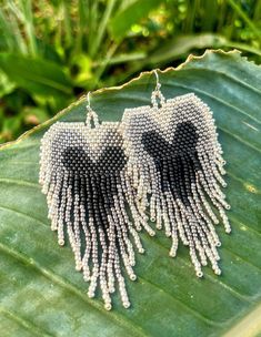 two pairs of beaded heart shaped earrings on top of a green leaf in the sun