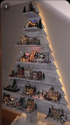 a christmas tree made out of wooden planks with lights and houses on the top