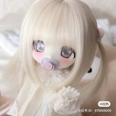 a doll with white hair and blue eyes laying on top of a bed next to a stuffed animal