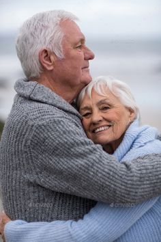 an older couple embracing each other on the beach