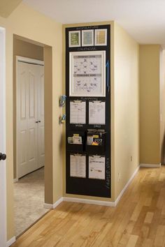 a wall mounted bulletin board in an empty room with wood flooring and yellow walls