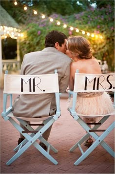 a man and woman sitting in chairs with mr and mrs signs on them