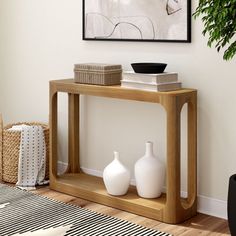 a table with two vases on it in front of a wall mounted art piece