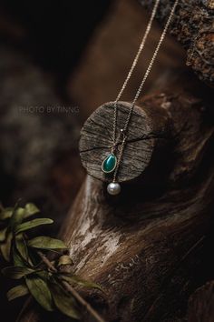 a wooden piece with a turquoise stone hanging from it's side on a tree branch