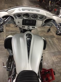 the front view of a white motorcycle parked in a showroom with other motorcycles behind it