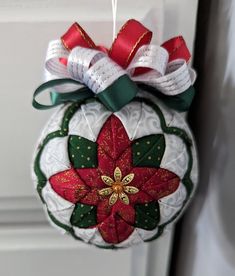 a christmas ornament hanging from a door with red and green ribbons on it