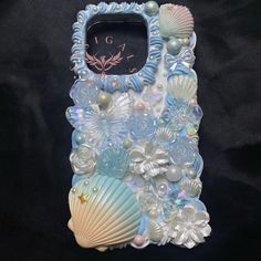 a cell phone case made out of shells and seashells on a black background