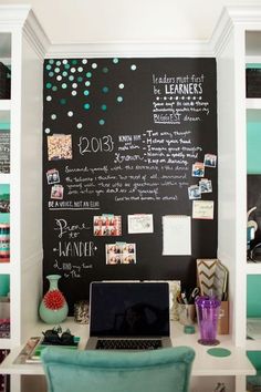 a desk with a laptop on it and a chalkboard in the corner behind it