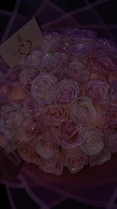 a bouquet of pink roses with water droplets on it and a card in the middle