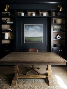 a large wooden table sitting in front of a black book shelf filled with books and vases