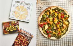 a pizza sitting on top of a cooling rack next to boxes of chips and other food