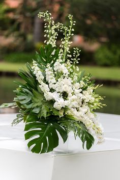 a vase filled with white flowers and greenery