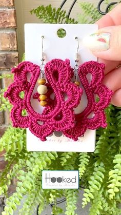 a pair of pink crocheted earrings sitting on top of a card