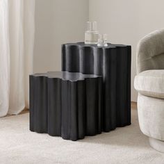 three black tables sitting on top of a white carpeted floor next to a chair