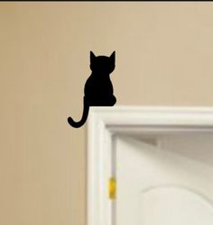 a black cat sitting on top of a door