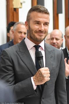 a man in a suit and tie holding a microphone while standing next to other men