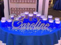 a blue table topped with candles and a name sign on it's centerpiece