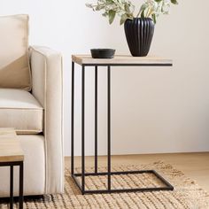 a living room with a couch, table and vase on the floor next to it