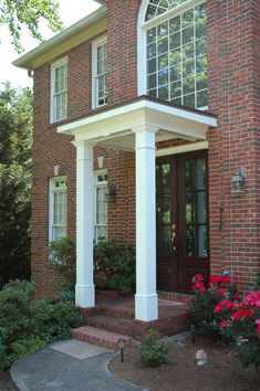 a brick house with white columns and flowers on the front steps in front of it