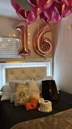 balloons are hanging from the ceiling above a bed with pillows and other items on it