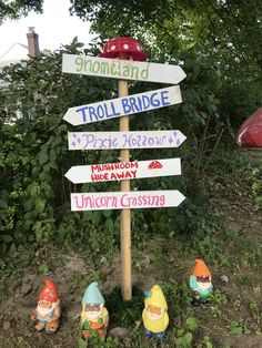 several gnomes are standing next to a sign that says troll bridge, frog hollow and unicorn crossing