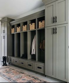 an organized mud room with gray cabinets and baskets on the wall, carpeted floor