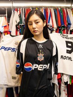 a young woman standing in front of a rack of soccer jerseys and t - shirts