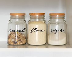 three jars with cereal flour, sugar and oatmeal in them on a shelf