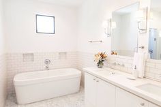 a large white bathroom with two sinks and a bathtub