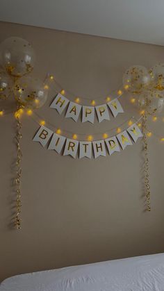 balloons and streamers are hanging on the wall above a bed in a bedroom with a happy birthday banner