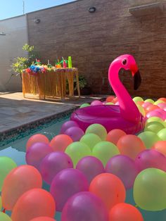 an inflatable flamingo floating on top of a pool filled with balloons