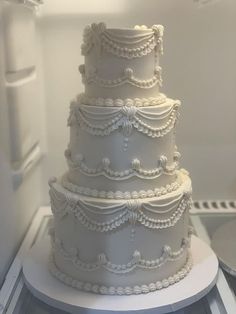 a three tiered white cake sitting on top of a refrigerator