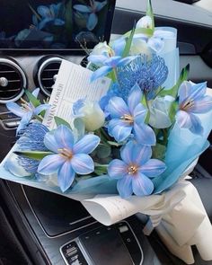 a bouquet of blue flowers sitting on top of a car dashboard