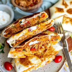 two quesadillas stacked on top of each other with tomatoes and sour cream