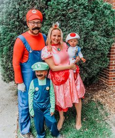 a family dressed up as mario and luigi from mario bros posing for a photo in front of some bushes