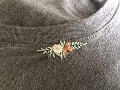 a close up of a sweater with flowers on it's chest and an embroidered applique