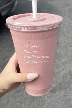 a person holding up a pink smoothie in front of a car with the words strawberry banana vanilla protein coconut water on it