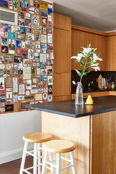 two stools sit in front of a kitchen island with an arrangement of pictures on the wall behind it