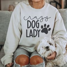 a woman sitting on a couch with her dog and wearing a sweatshirt that says, mays dog lady