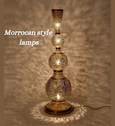 the moroccan style lamp is lit up with three lights on each side, and has an intricate design