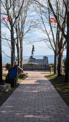 there is a statue in the middle of this park with trees and benches around it